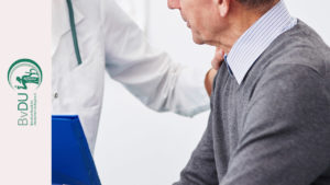 Ärztin legt Hand auf die Schulter von einem älteren Patienten
