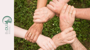 Fünf Personen fassen kreisförmig jeweils an das Handgelenk des nächsten.