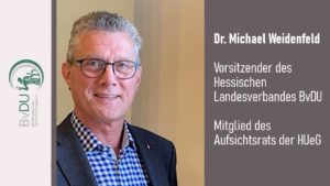 Porträt eines grauhaarigen Mannes mit Brille, Hemd und Jacket.