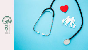 Ein Stethoskop als Rahmen um ein Herz und eine Papierfamilie gelegt.