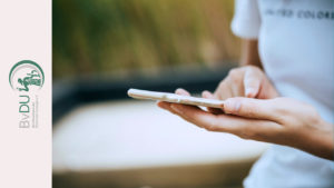 Eine Person hält ein Smartphone und tippt darauf.